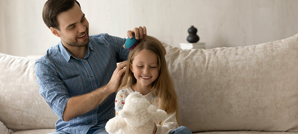 Father combing his daughter's hair.