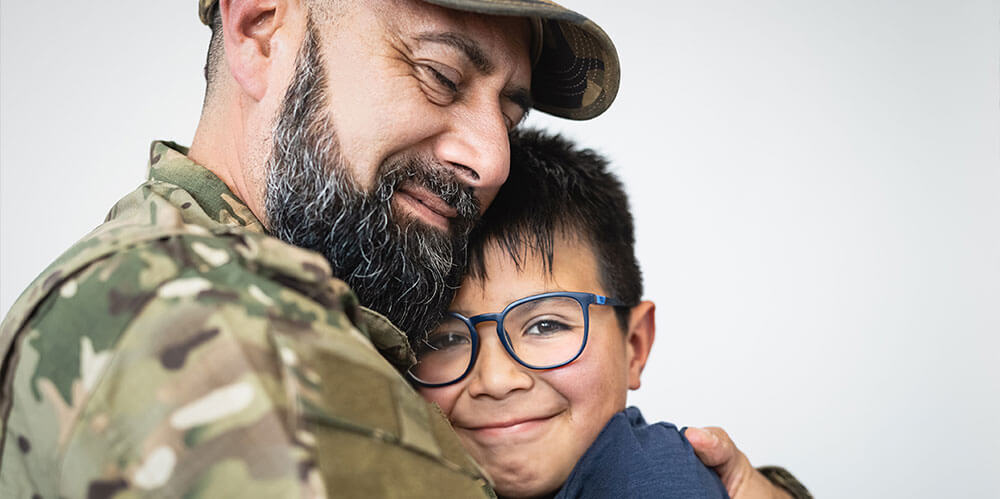 A father in the military holds his smiling son close to him