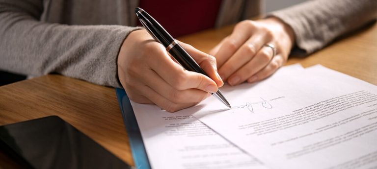 A person signing a small succession affidavit with a pen.