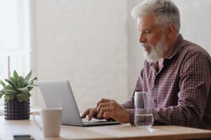 An elderly man searches what an ancillary probate is on his laptop.