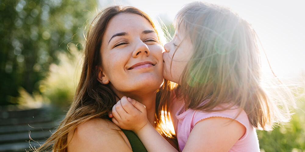a little girl kissing her mom on the cheek